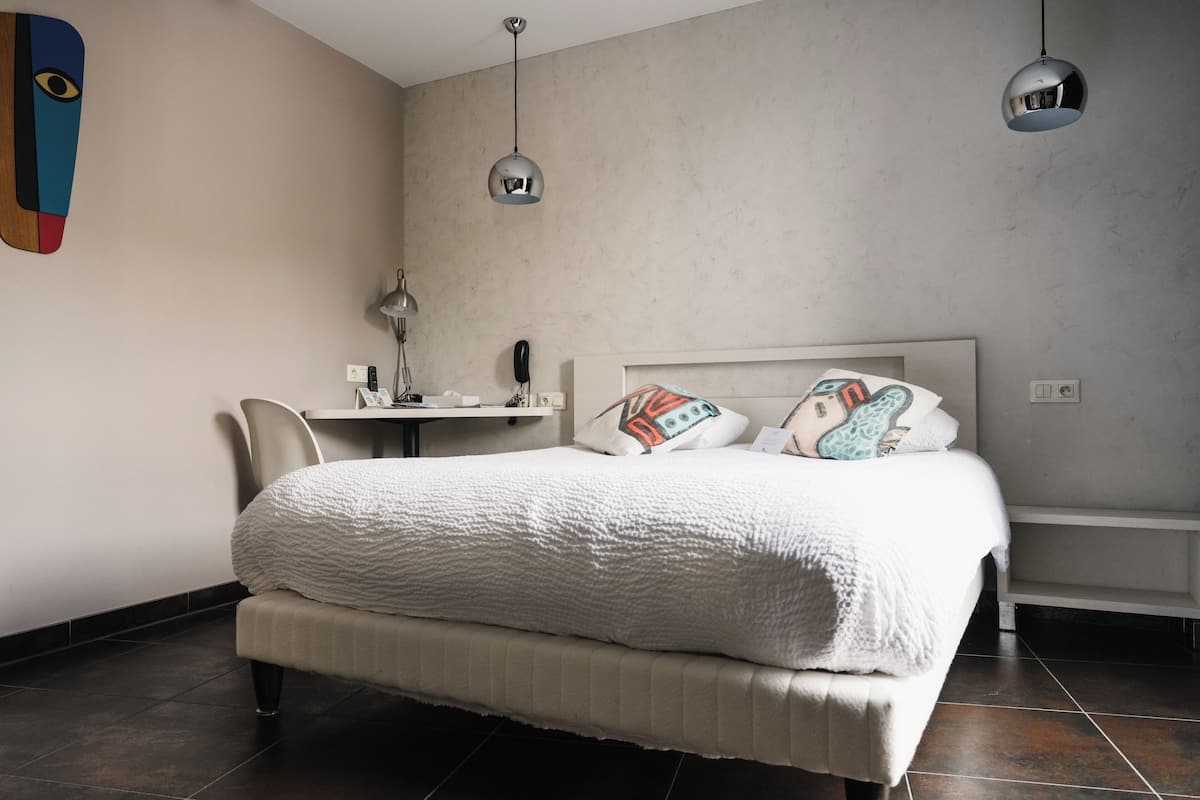 A modern bedroom with a large bed, a desk, and a chair.