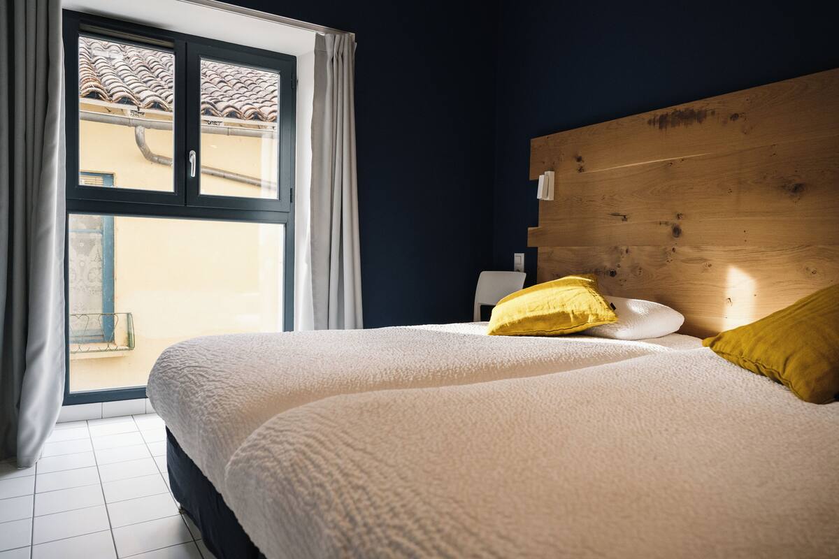 A bedroom with a large bed, a wooden headboard, and a view through a window.
