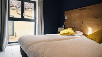 A bedroom with a large bed, a wooden headboard, and a view through a window.