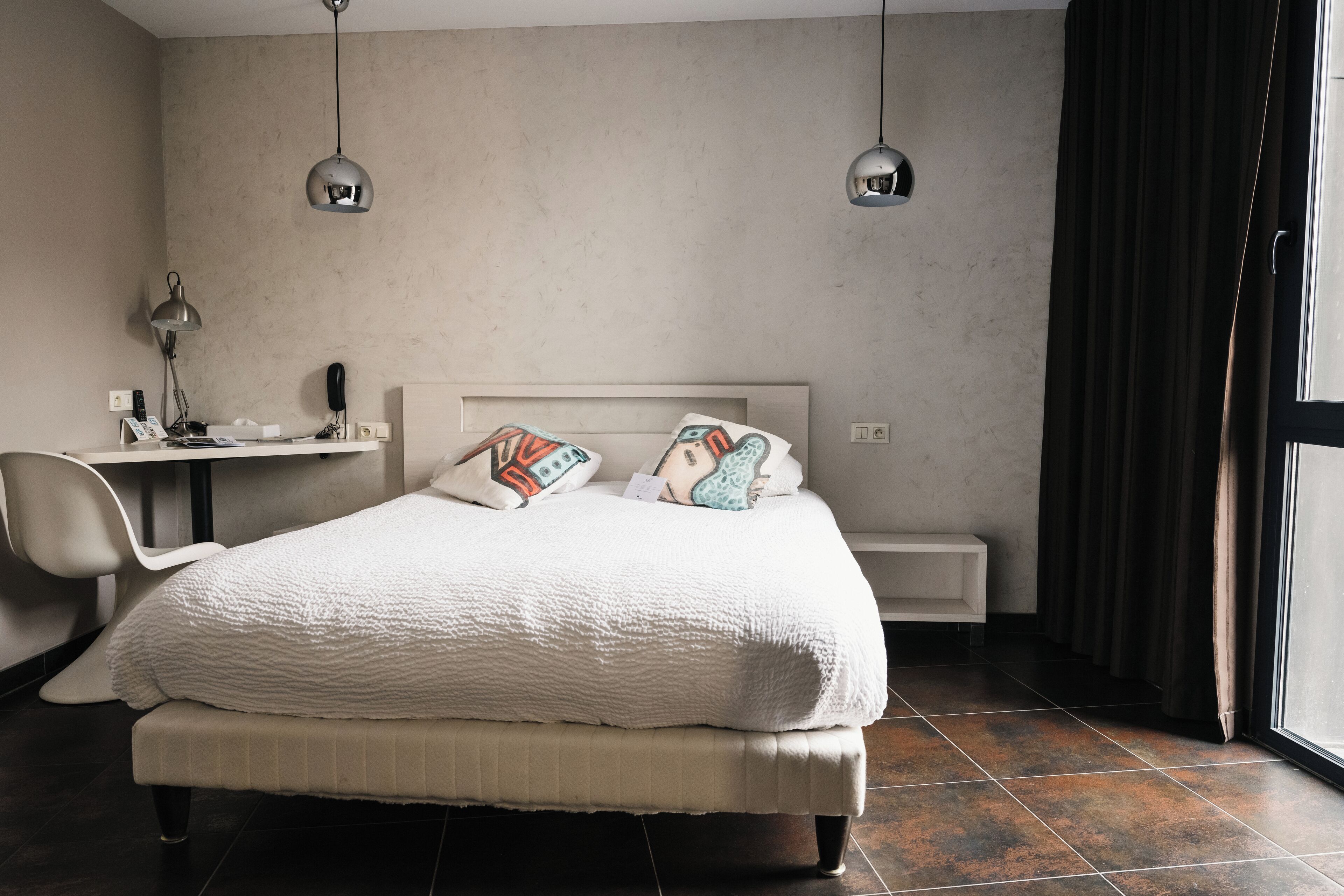 Une chambre avec un grand lit, un bureau et deux lampes suspendues.
