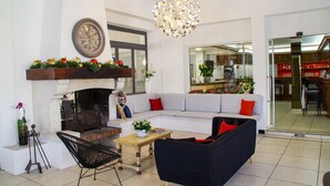 Un salon avec une cheminée, un ensemble de canapés, une table basse en bois et un lustre.