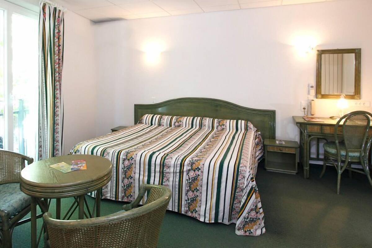 A room with a bed, a desk, a chair, and a table.