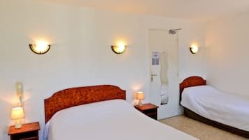 A hotel room with two beds, each with a wooden headboard, a nightstand with a lamp, and wall-mounted light fixtures.