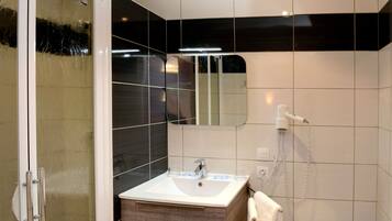 Une salle de bain moderne avec une douche à parois de verre, un lavabo avec un miroir et des toilettes.