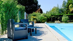 A poolside area with outdoor seating and a clear view of the pool. - Chez Germaine (Geus-d'Oloron)