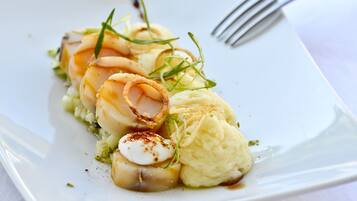 A plate of food with scallops, mashed potatoes, and garnishes.
