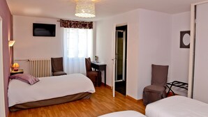 A hotel room with two beds, a desk, a chair, a radiator, and a television. - Chez Germaine (Geus-d'Oloron)