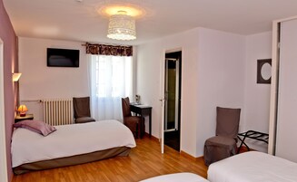 A hotel room with two beds, a desk, a chair, a radiator, and a television.