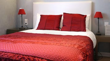 A hotel room with a large bed, red bedding, and two bedside lamps.