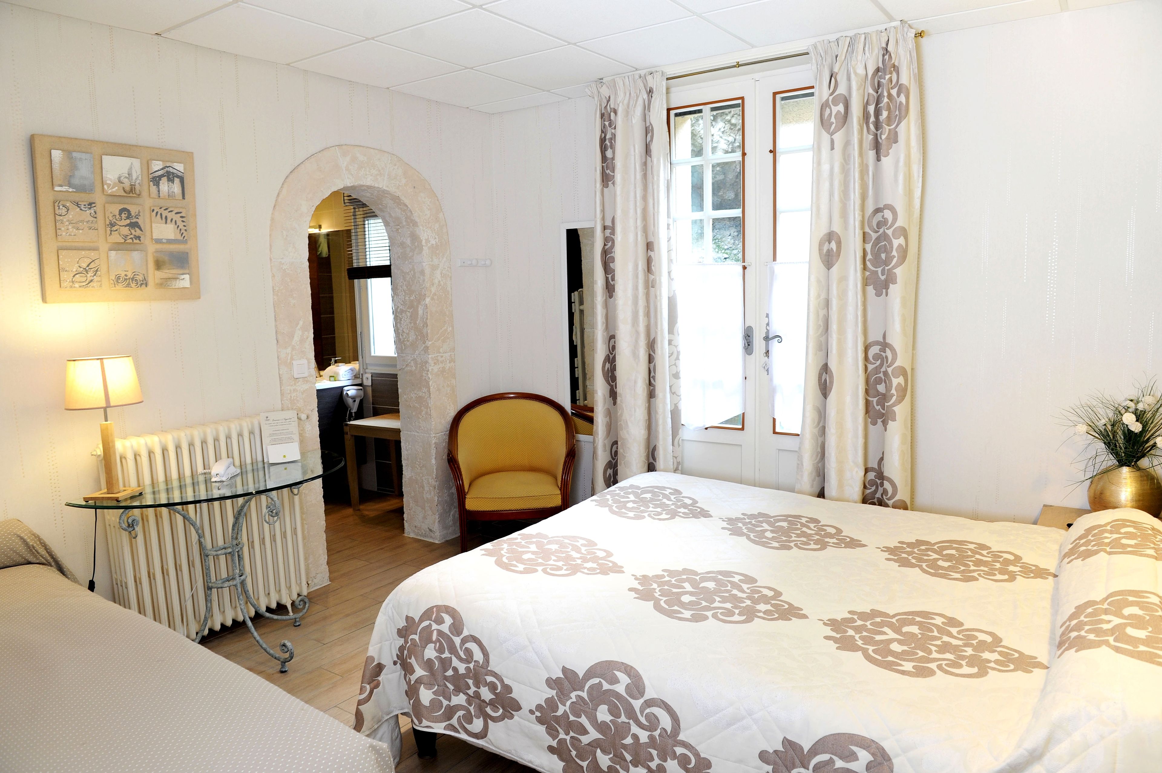 A hotel room with a bed, a chair, a table, and a radiator.