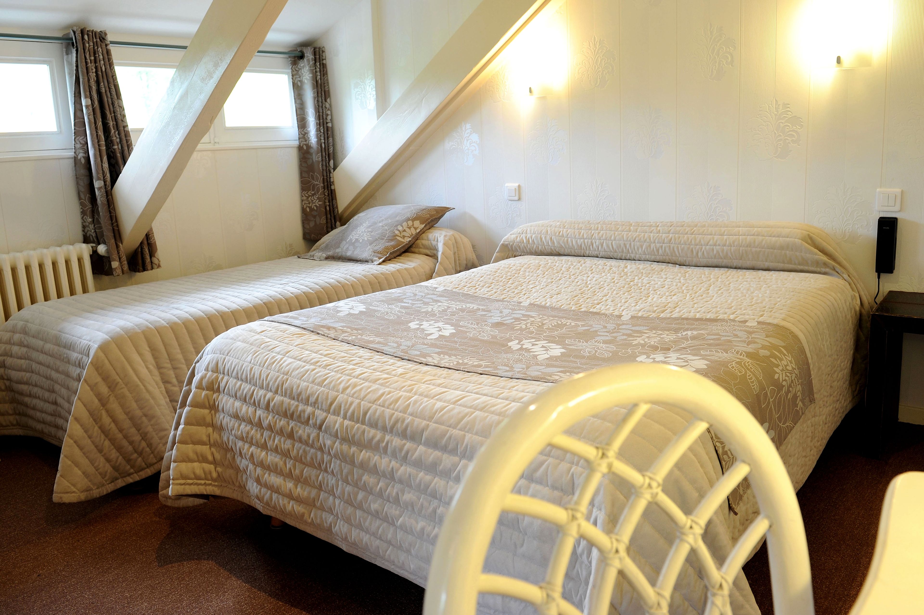 A bedroom with two beds, a white chair, and a radiator.