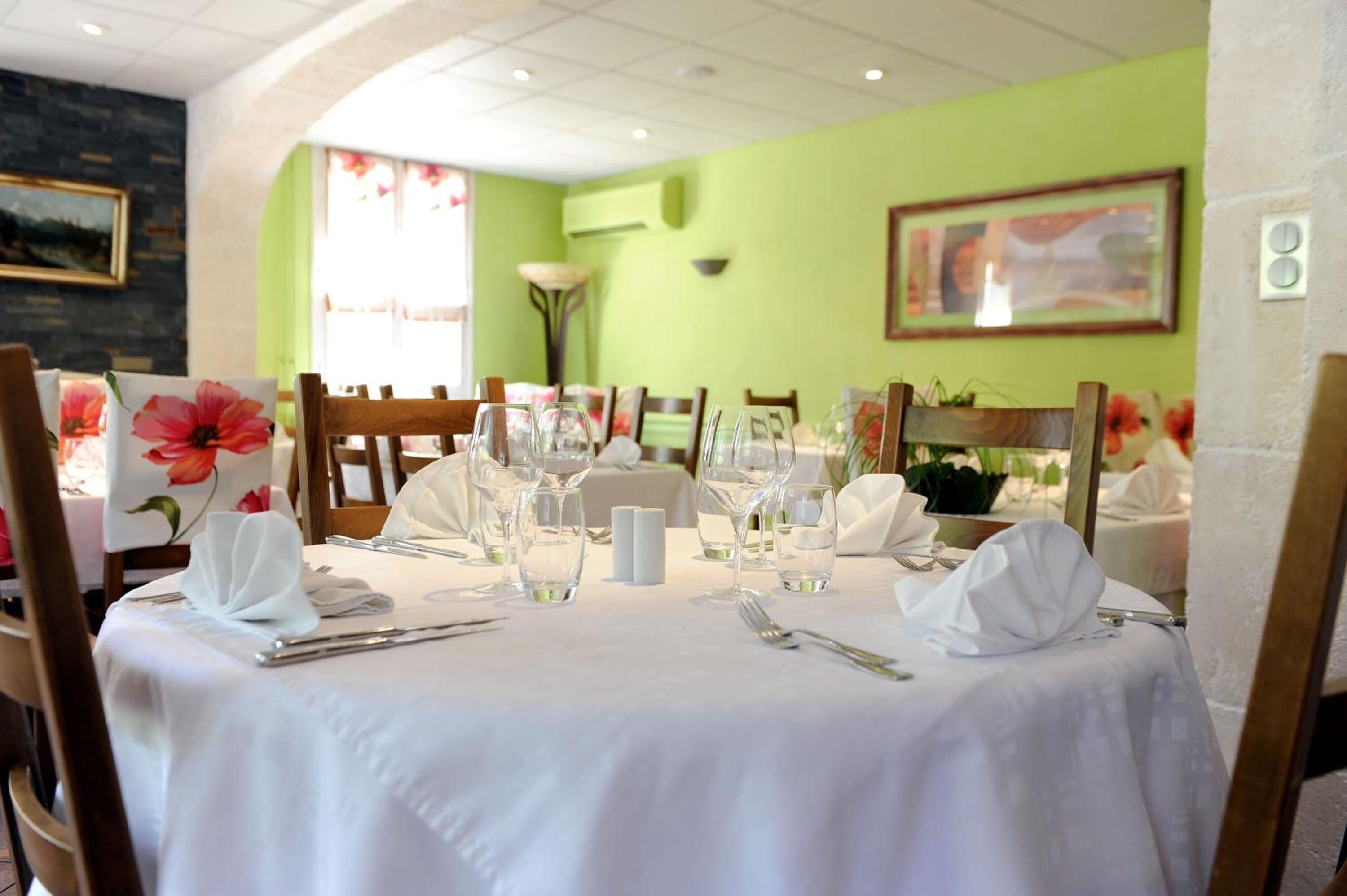 A dining area with tables set for two, white tablecloths, and chairs.