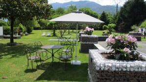 An outdoor patio with tables and chairs, surrounded by greenery and a mountain view. - L'Ayguelade (Bielle)