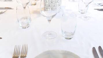 Una mesa dispuesta con un mantel doblado, dos tenedores, una copa y un florero decorativo con una planta.