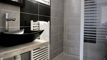 A bathroom with a black vessel sink, a towel rack, and a window with blinds.