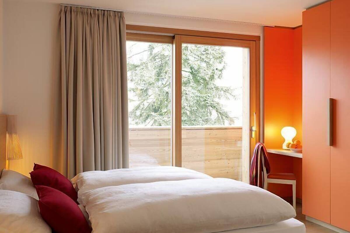 Habitación de hotel con cama, escritorio y vistas a los árboles.