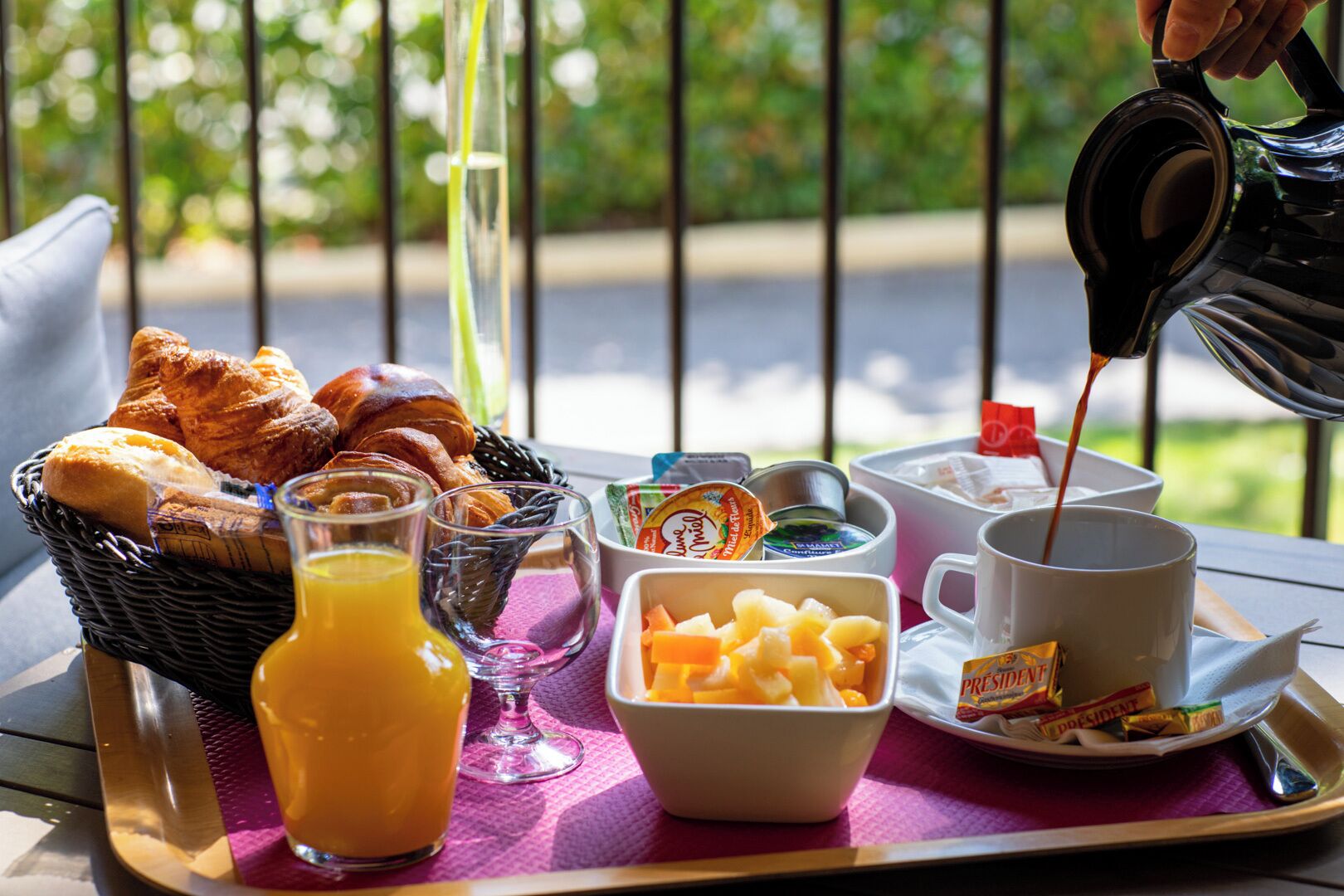 A breakfast tray with croissants, orange juice, yogurt, and a cup of coffee.