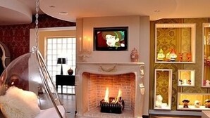 A modern living room with a fireplace, a hanging chair, and a television mounted above it.