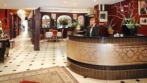 A hotel lobby with a reception desk, seating area, and decorative plants.