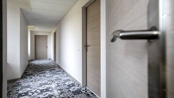 Un pasillo con baldosas de diseño, una puerta de madera con manija y un techo de color claro.