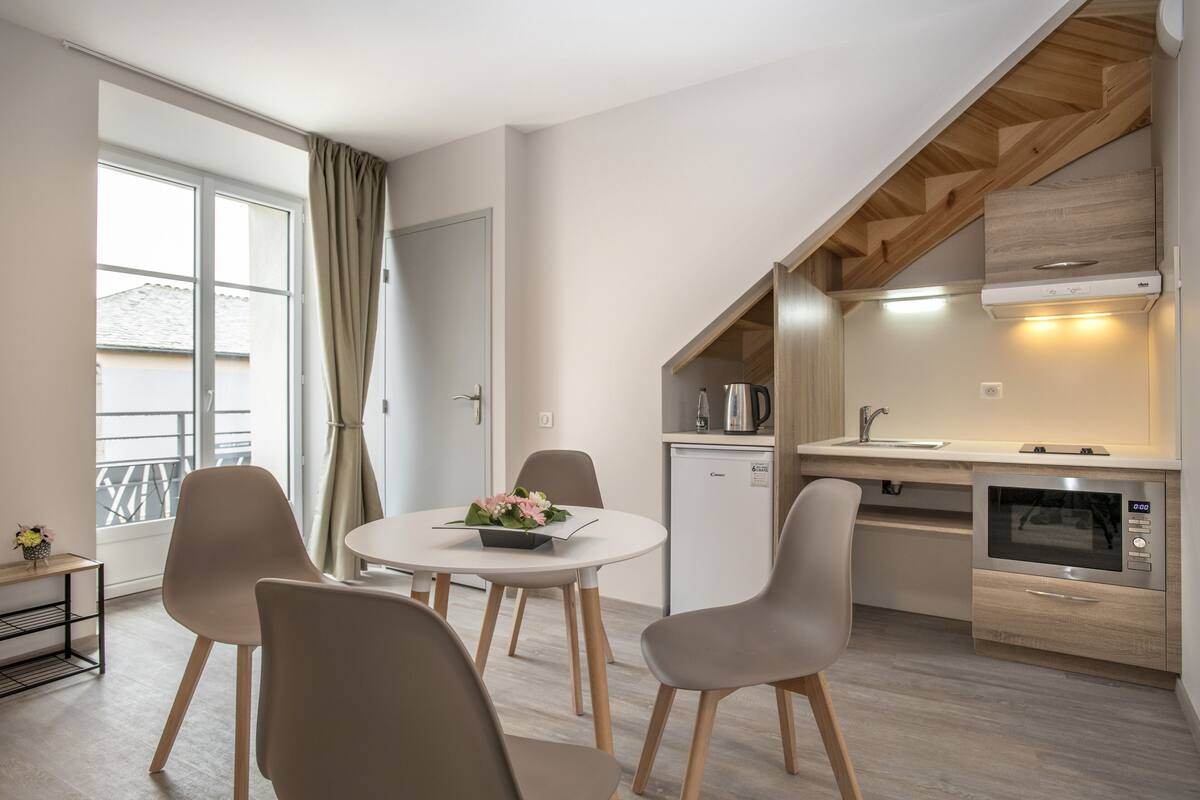 Una cocina moderna con horno integrado y una zona de comedor con mesa redonda y cuatro sillas.