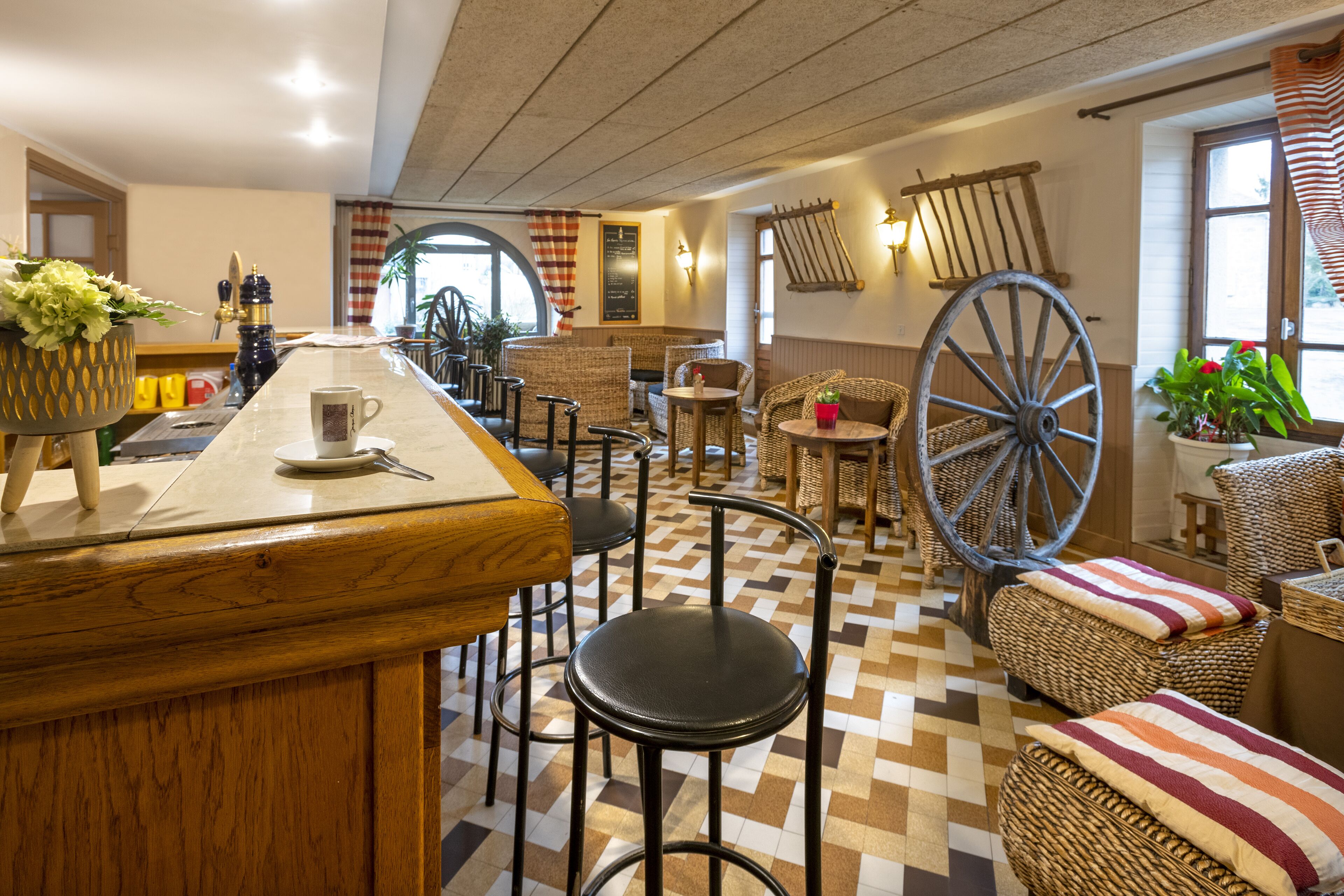 A restaurant with a bar area, wicker furniture, and a large wooden wheel.