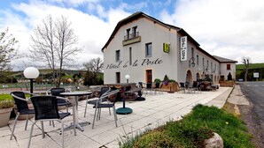A building labeled "Hotel de la Poste" with outdoor seating and a sign indicating a restaurant. - Hôtel Restaurant de la Poste et La Grange Détente, espace bien-être (Chateauneuf-de-Randon)