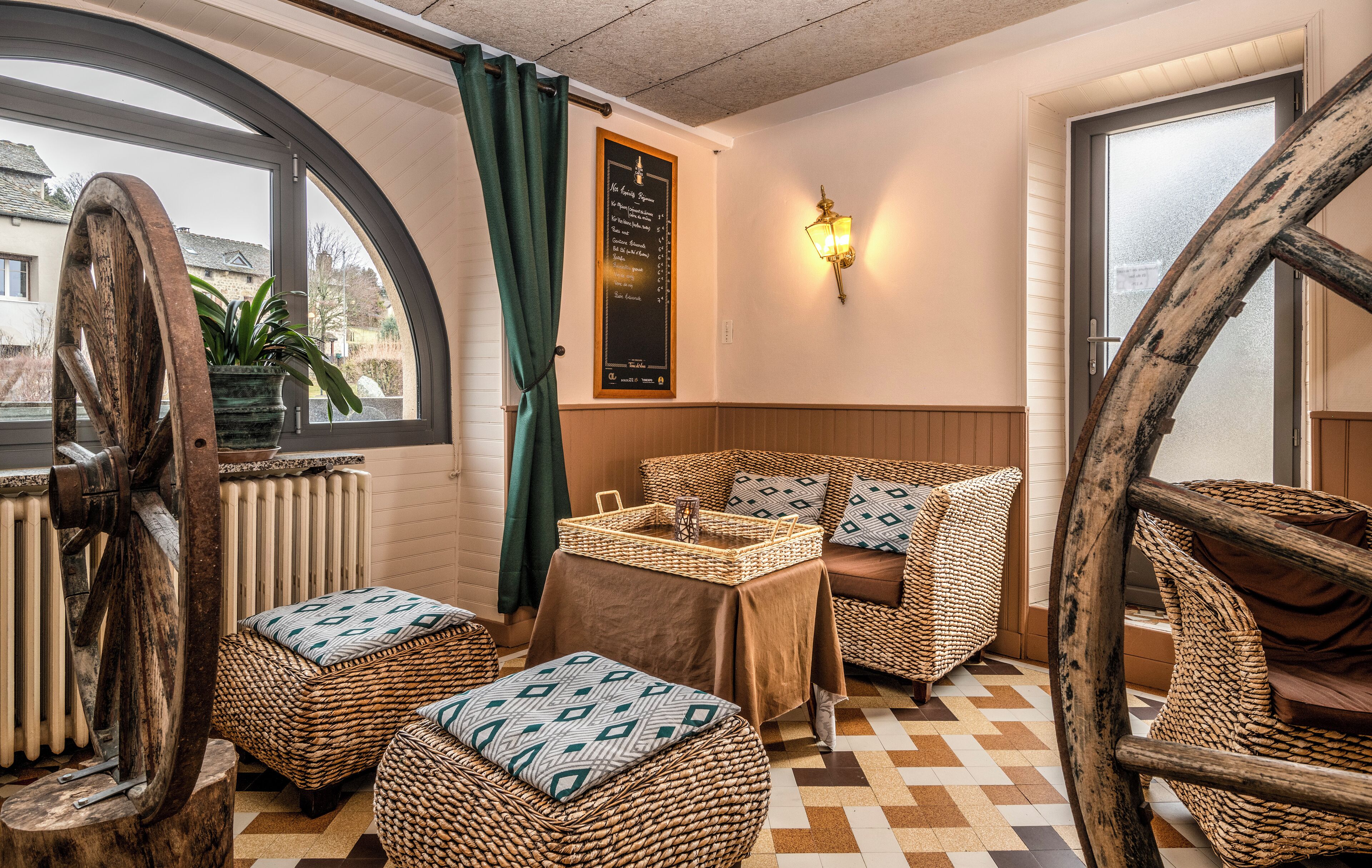 A cozy room with wicker furniture, a table with a tray, and a view through a large window.
