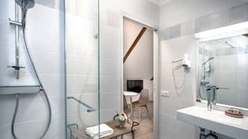 A modern bathroom with a glass shower enclosure, a white sink, and a small table with a vase.