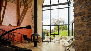 A spacious room with a large window, a fireplace, and modern white chairs. - Hôtel Restaurant de la Poste et La Grange Détente, espace bien-être (Chateauneuf-de-Randon)