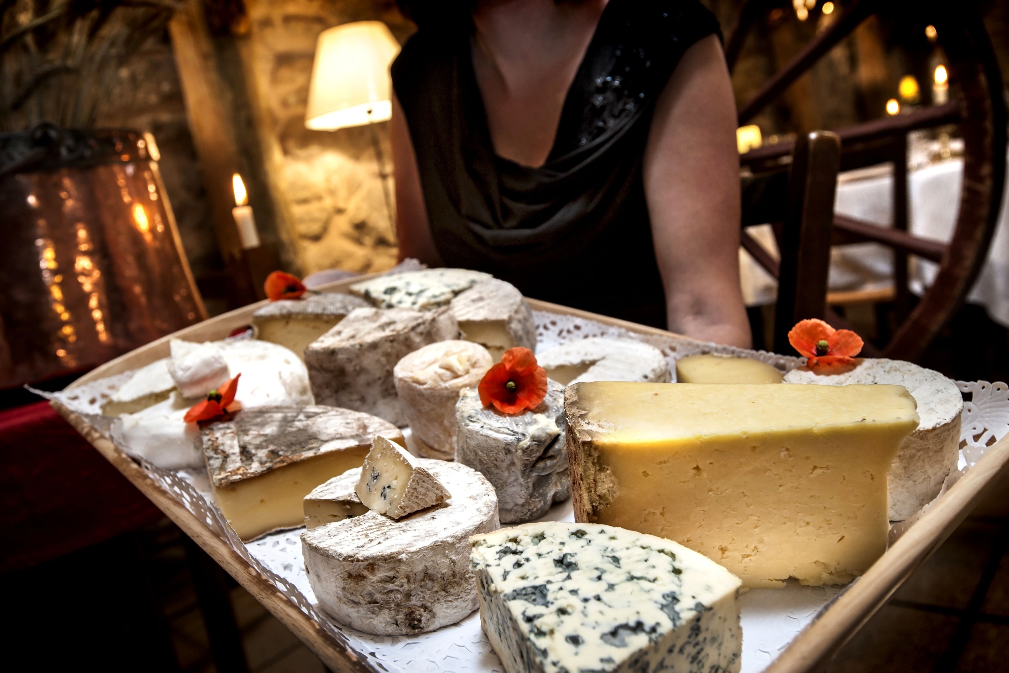 Une variété de fromages présentés sur un plateau, avec un décor intérieur rustique en arrière-plan.