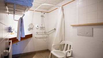 Un baño con ducha, inodoro, lavamanos y una silla.