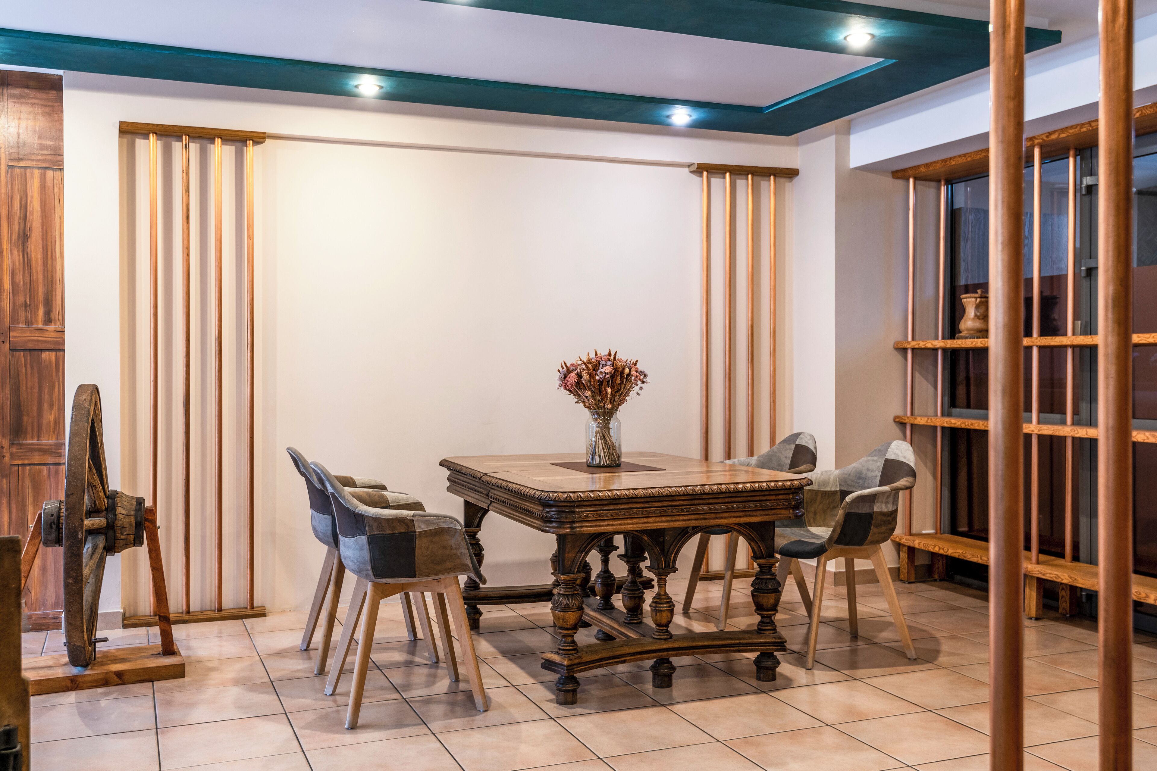 A dining area with a wooden table and chairs, a vase with dried flowers, and a wooden cabinet.