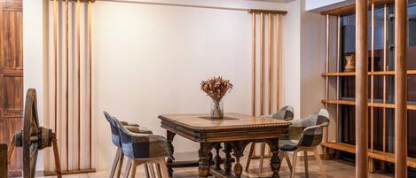 A dining area with a wooden table and chairs, a vase with dried flowers, and a wooden cabinet.