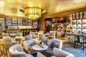 A bar area with a variety of bottles, a seating area with round tables and chairs, and a decorative ceiling light. - Crowne Plaza Beijing Chaoyang U-Town by IHG (Beijing)