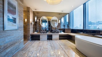 Un baño moderno con una bañera grande, suelo de mármol y espejos amplios.
