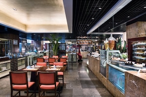 Un restaurante moderno con un área de comedor central, una barra con vitrina y diversas opciones de comida.