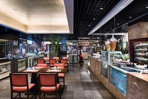 Ein modernes Restaurant mit einem zentralen Essbereich, einer Theke mit einer Auslage und einer Auswahl an Speisen.