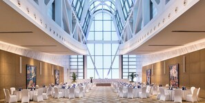 A spacious conference room with high ceilings and large windows, arranged for a formal event with round tables and white chairs. - Crowne Plaza Beijing Chaoyang U-Town by IHG (Beijing)