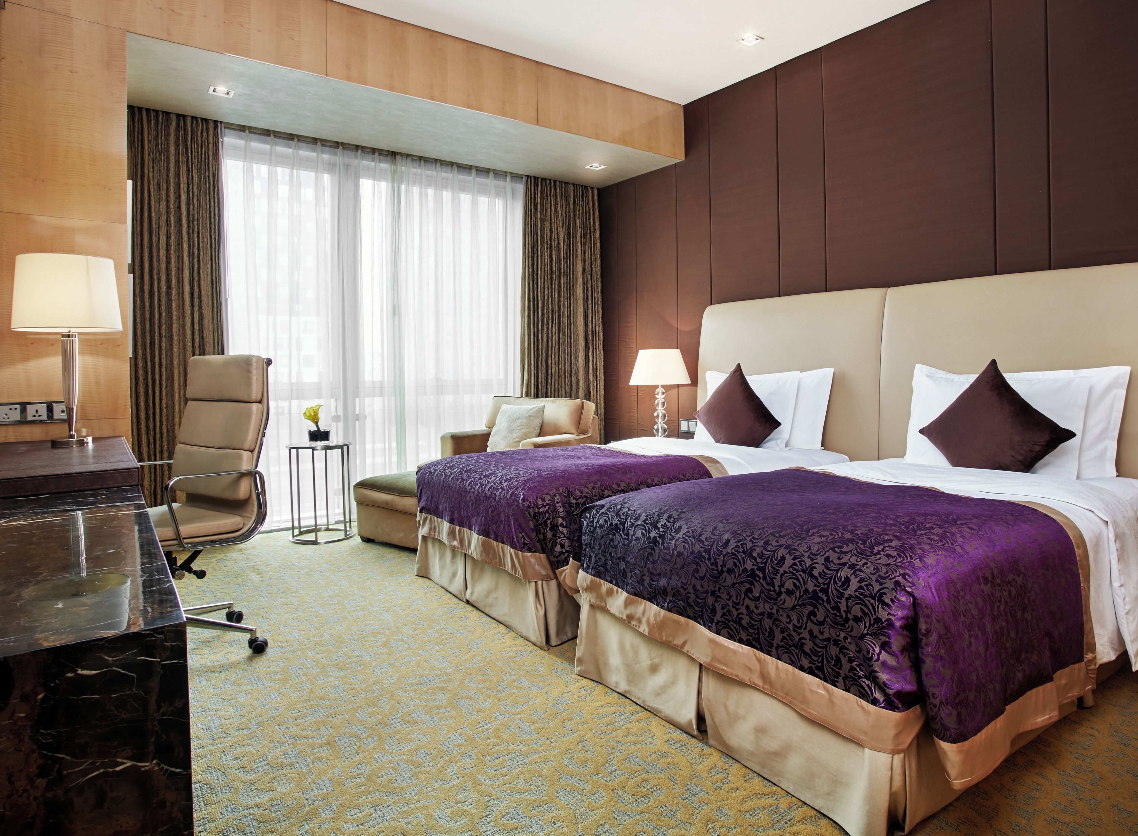 Ein Hotelzimmer mit einem großen Bett, einem Schreibtisch, einem Stuhl und einem kleinen Tisch.
