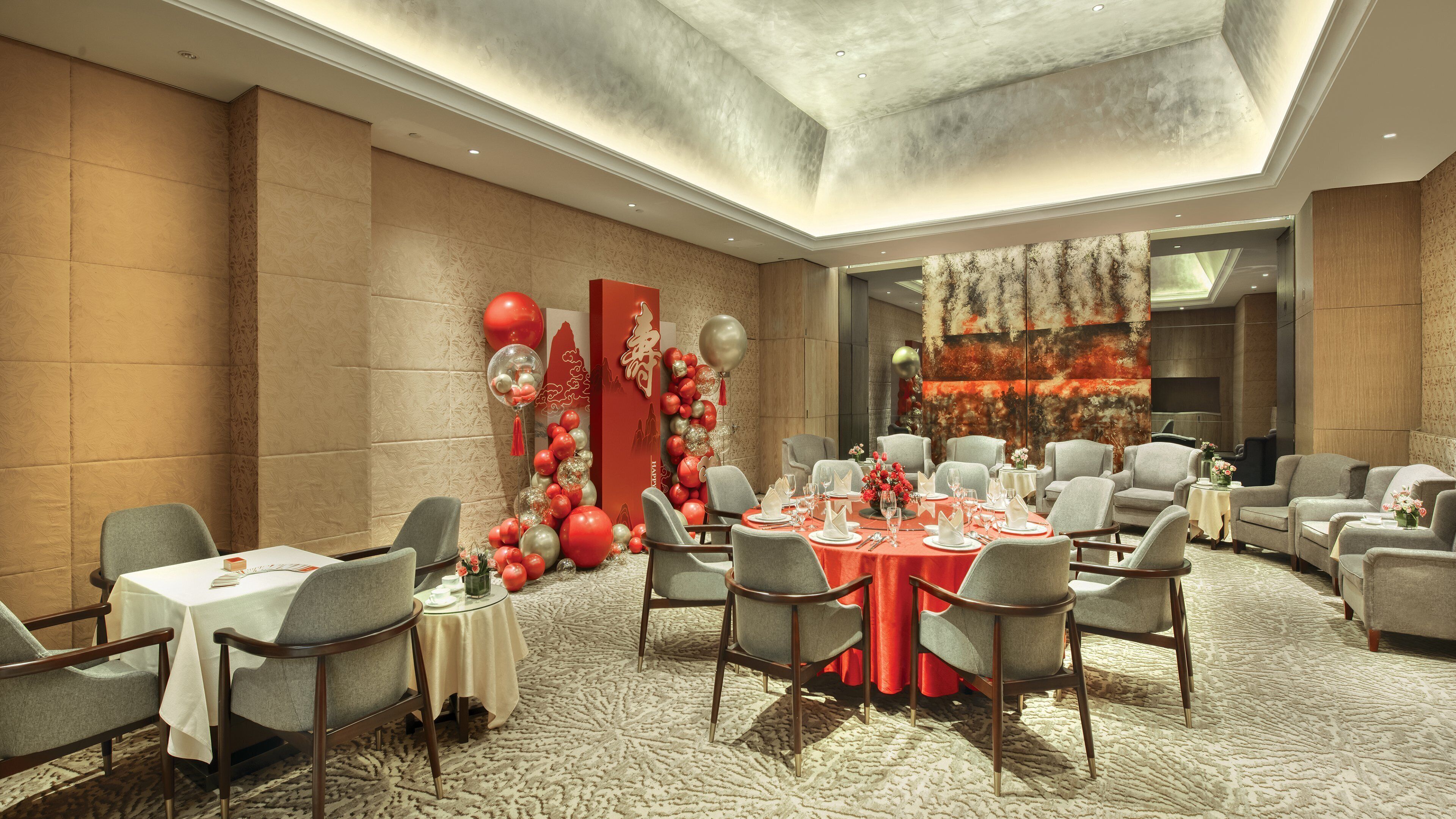 A banquet hall with round tables, grey upholstered chairs, and a carpeted floor.