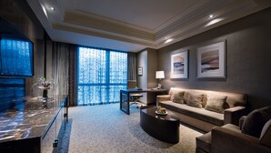 A modern living room with a marble reception desk, a sofa, a coffee table, and a large window with curtains.