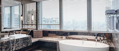 A modern bathroom with a large bathtub, a vanity with a marble countertop, and a large mirror.