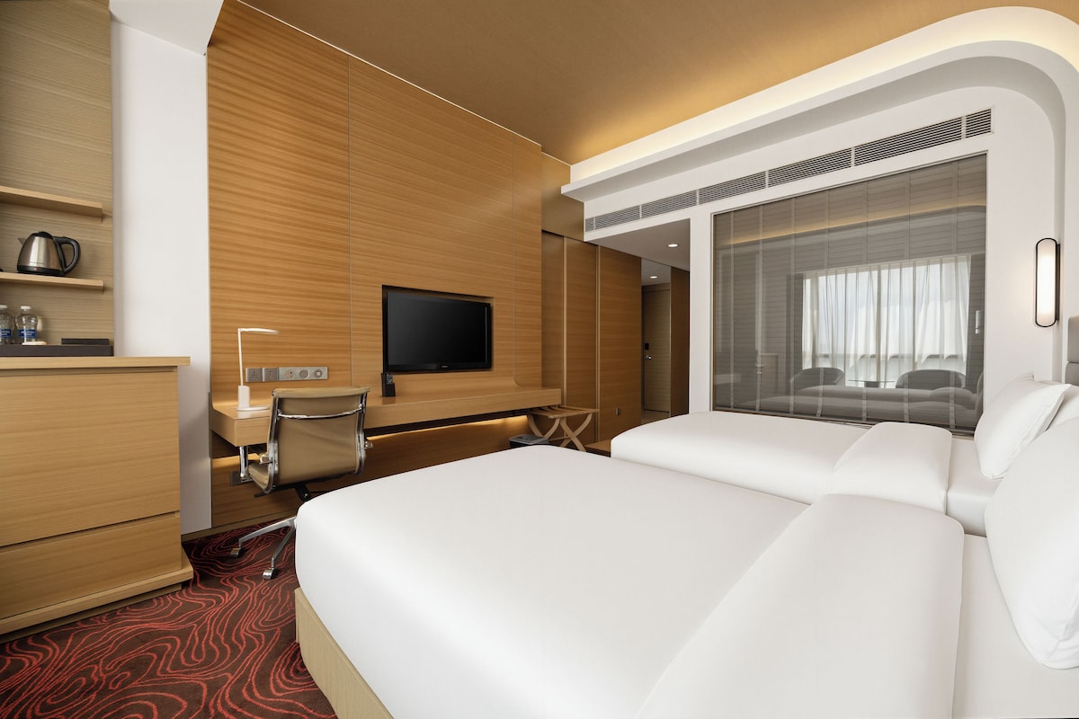 Een moderne hotelkamer met een groot bed, een bureau met stoel, een flatscreen-tv en een minibar.