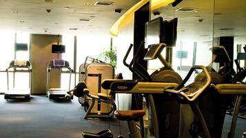 Ett gym med olika typer av träningsutrustning, inklusive löpband och styrketräningsmaskiner.