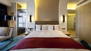 Une chambre d’hôtel avec un grand lit, un bureau, une chaise et un espace douche.