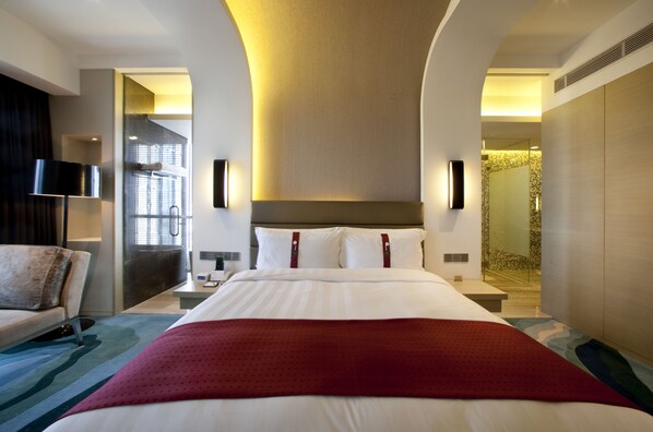 Ein Hotelzimmer mit einem großen Bett, einem Schreibtisch, einem Stuhl und einer Duschkabine.