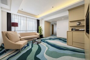 A modern hotel room with a sofa, a coffee table, a plant, and a kitchenette area. - Holiday Inn Shanghai Songjiang by IHG (Shanghai)