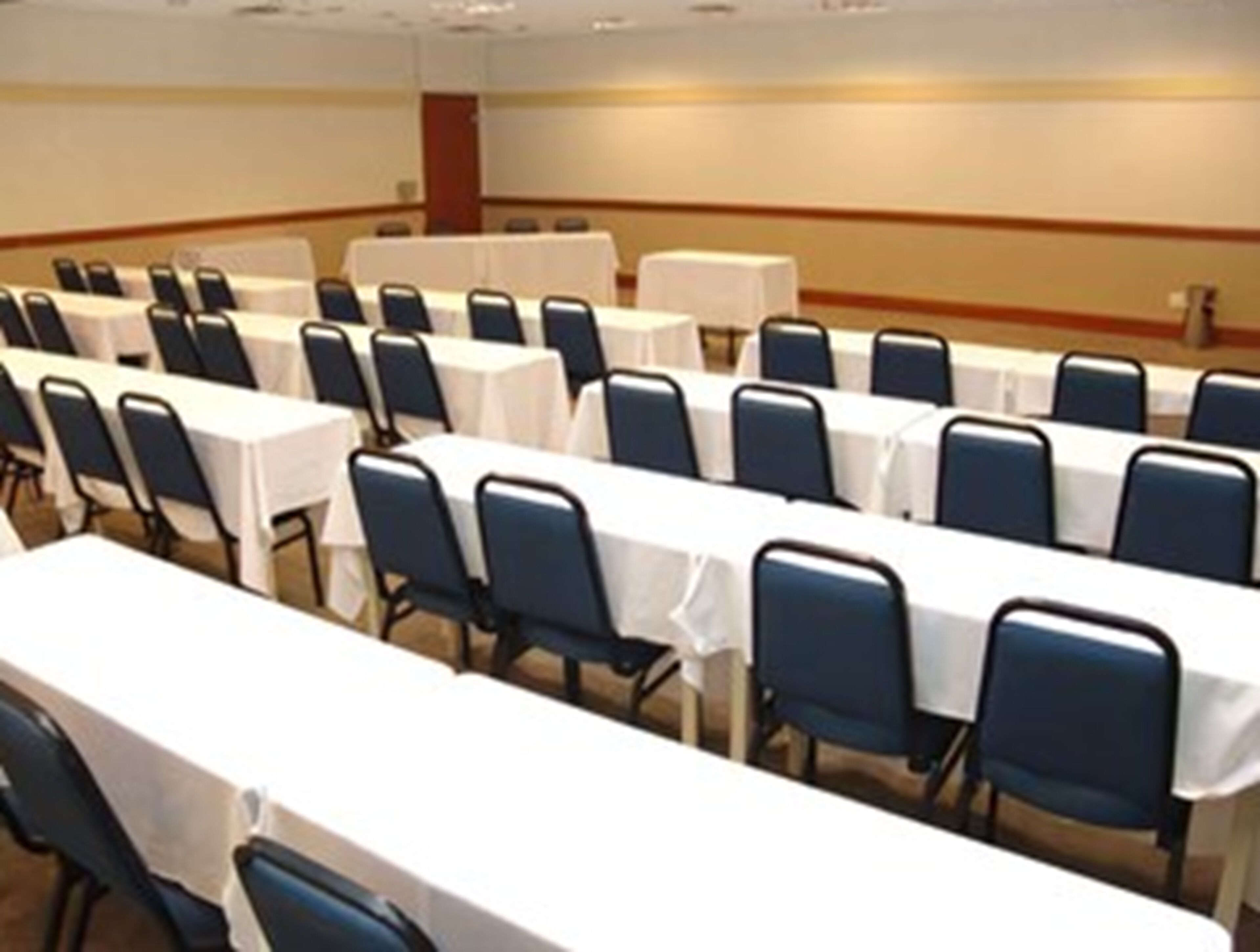 A conference room with rows of tables and chairs, arranged in a U-shape.