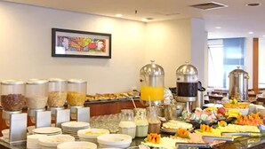 A buffet setup with various food items and beverages, including cereal, fruits, and a coffee machine. - Travel Inn Hotels Ibirapuera (São Paulo)